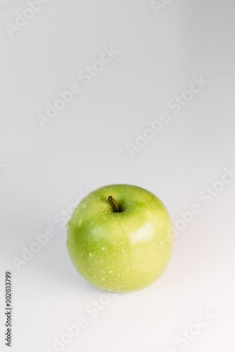 Fresh green apples with water droplets on a white glossy kitchen table. Tasty bright juicy fruits. Healthy eating. Isolated object.