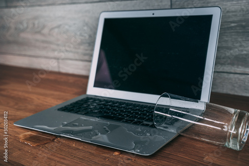 Glass of spilled water on laptop