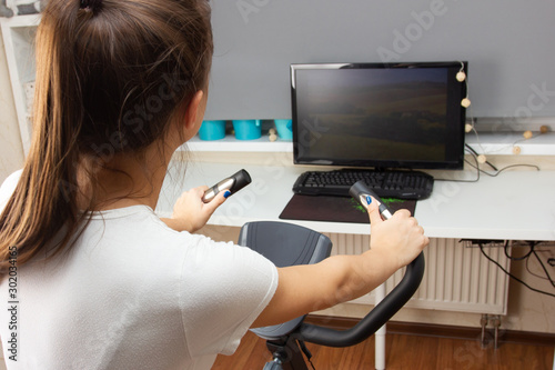 Young girl is engaged on a stationary bike at home