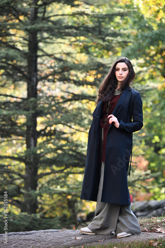 Beautiful young woman in elegant coat walking outdoors in autumn enjoying nature and weather.
