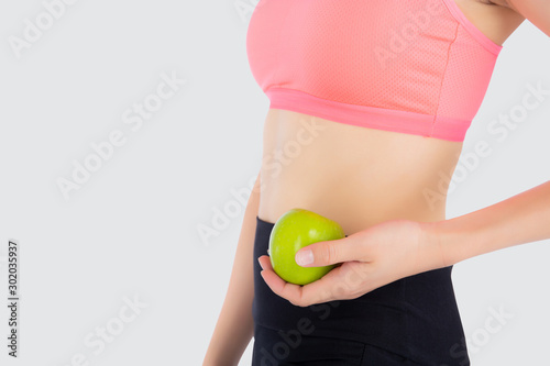 Closeup beautiful young asian woman in sport clothing satisfied and holding green apple isolated on white background, girl asia have shape and wellness, exercise for fit with health concept. © N_studio