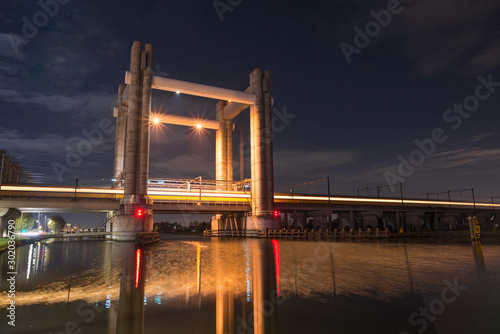 Train passes by at high speed on a railway lifting bridge over a river in Holland photo