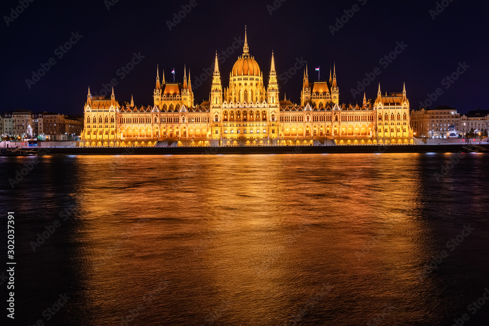 Naklejka premium Illuminated historical building of Hungarian Parliament at night on Danube River Embankment
