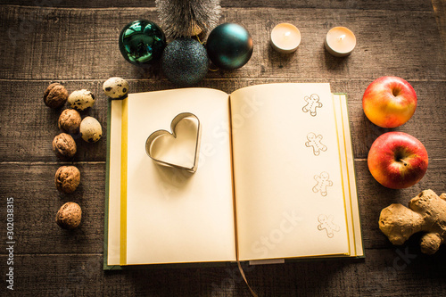 Christmas collage with notebook, ginger, quail eggs, walnuts, baubles, apples and candles on wooden background photo