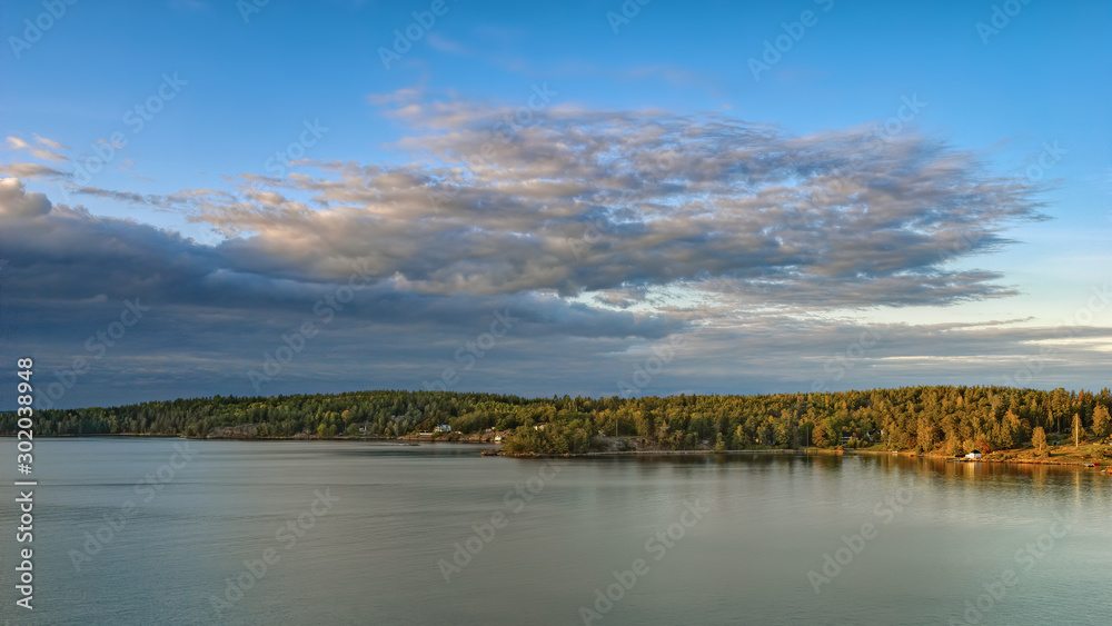 Rocky coast of Stockholm archipelago in Baltic sea with picturesque vacation houses at sunny autumn evening.
