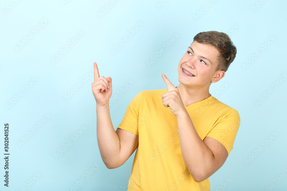Young man with dental braces pointing away on blue background Young man with dental braces pointing away on blue background
