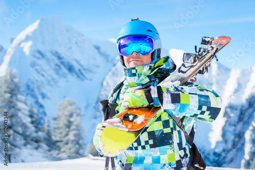 Photo of sports man in helmet and mountain skis against background of mountains in afternoon