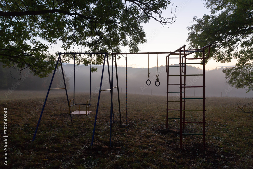 A set of children's sports equipment stands in the backyard, on a hill, against the forest. A set of children's sports equipment stands in the backyard, on a hill, against the forest.