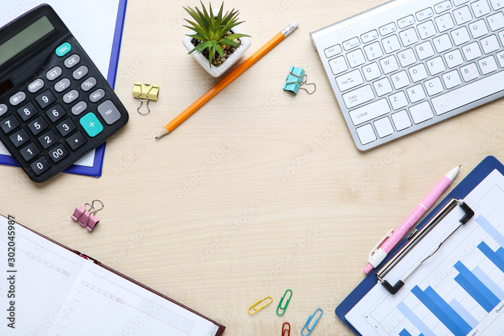 Financial paper with keyboard, calculator, notepad and green plant on wooden table Financial paper with keyboard, calculator, notepad and green plant on wooden table