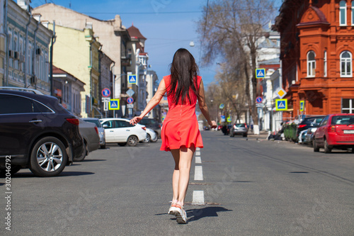 Young beautiful woman in red dress on the summer street © Andrey_Arkusha