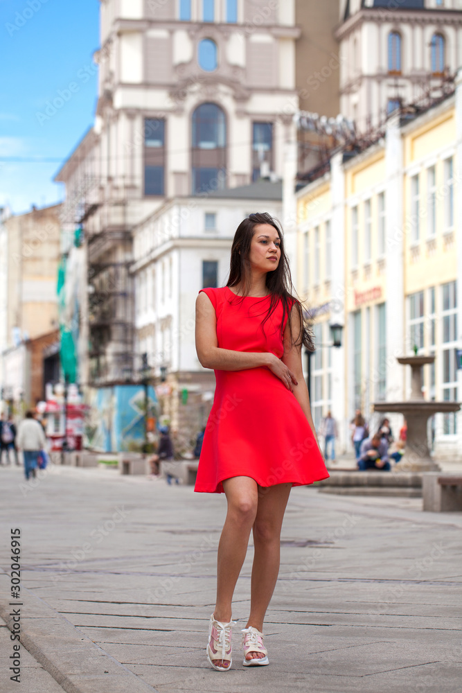 Young beautiful woman in red dress on the summer street