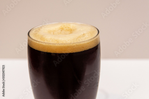 Dark beer with foam in a transparent glass