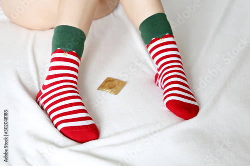 Woman with condom on the bed, contraception concept. Slim female legs in in christmas socks, romantic sex date in winter holidays