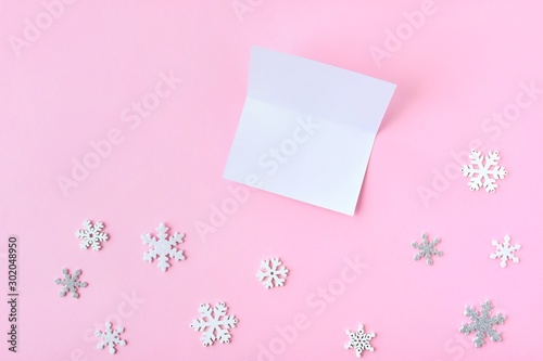 Pink Christmas background with white and silver snowflakes border and empty greeting card with selective focus. New year flat lay with snowflakes decorative border. Winter postcard.  © Tetiana Ivanova