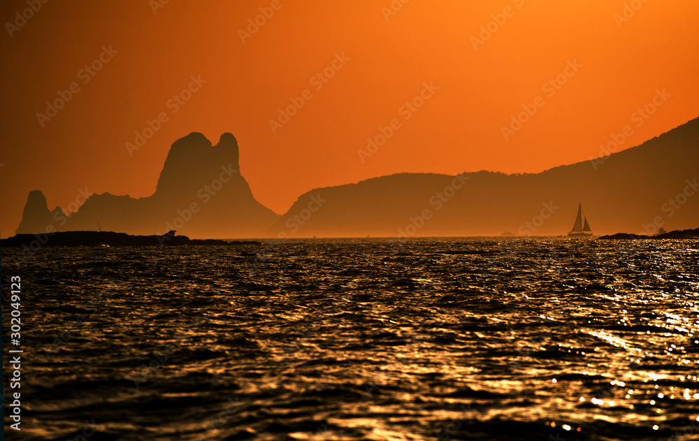 fantastic sunset with the mountains of the island of es ve with wonderful orange sky and sailboats in the background seen from the sea