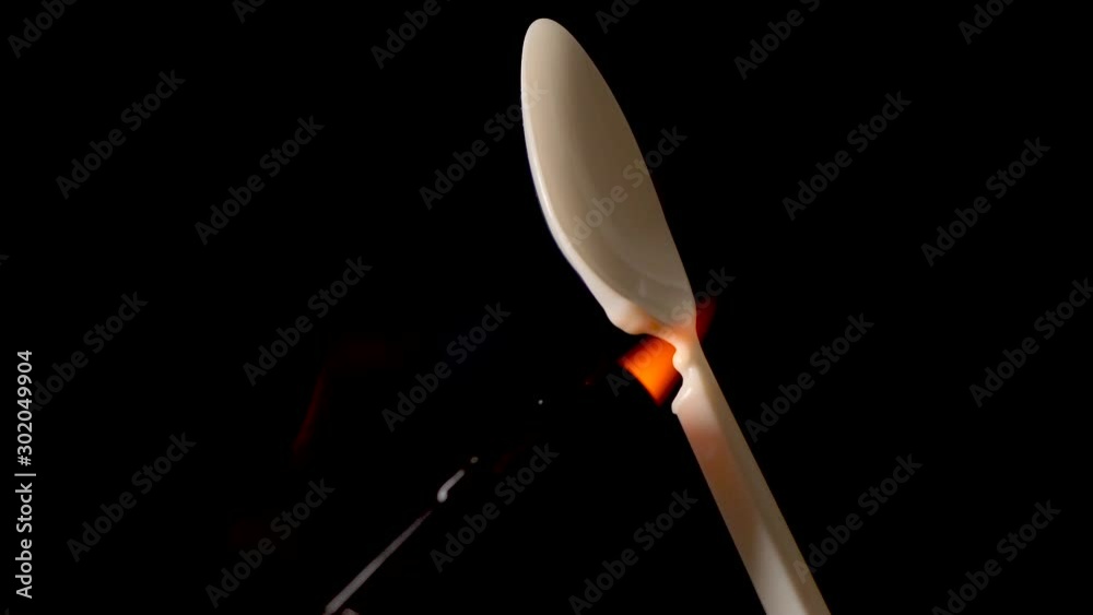 Torch melts plastic spoon on black background. Concept say no to plastic. Torch melts plastic spoon on black background. Concept say no to plastic.