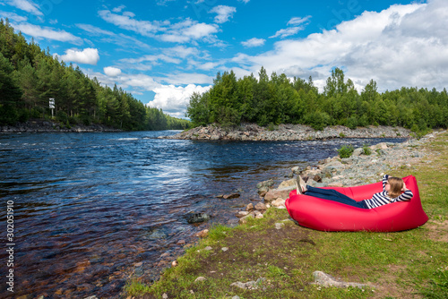 Young woman is relaxing in the red airlounger in the border of Fugga river in Hedmark county of Norway photo