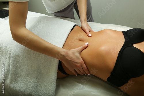 masseur doing massage of the muscles. the hands of a masseur do massage the abdomen closeup. photos for advertising massage services. anti-cellulite massage close-up.