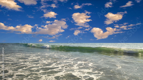blue sky with puffy clouds with waves breaking at Huntington Beach, CA