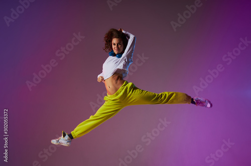 Bild auf Leinwand High jump of charming female dancer doing split leap in the air, performing mode