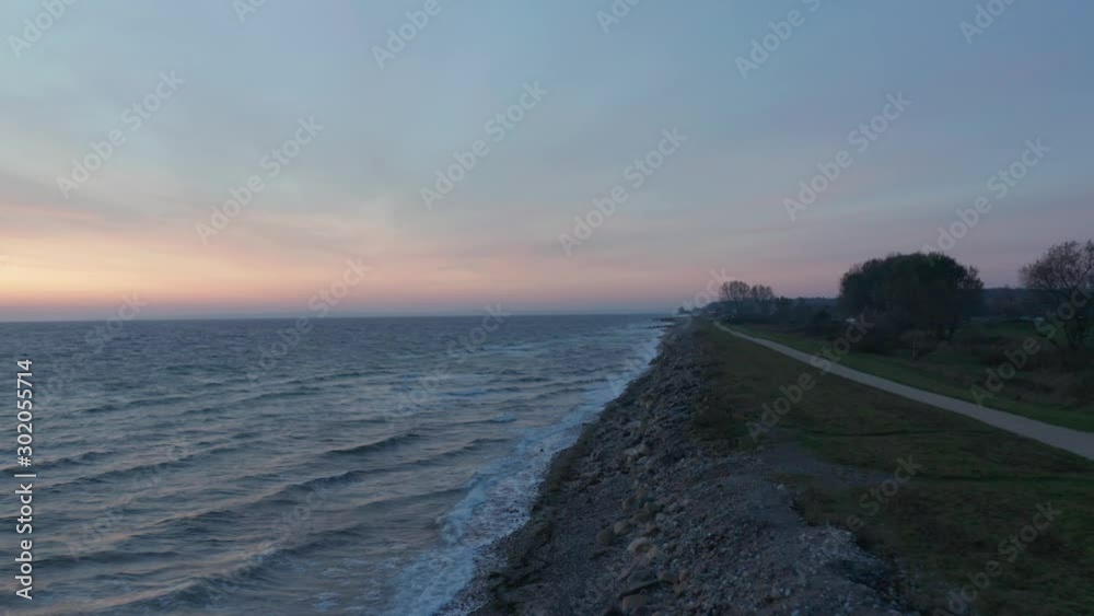 Aerial drone flight at baltic sea shoreline in Germany following a path towards the sunrise Aerial drone flight at baltic sea shoreline in Germany following a path towards the sunrise