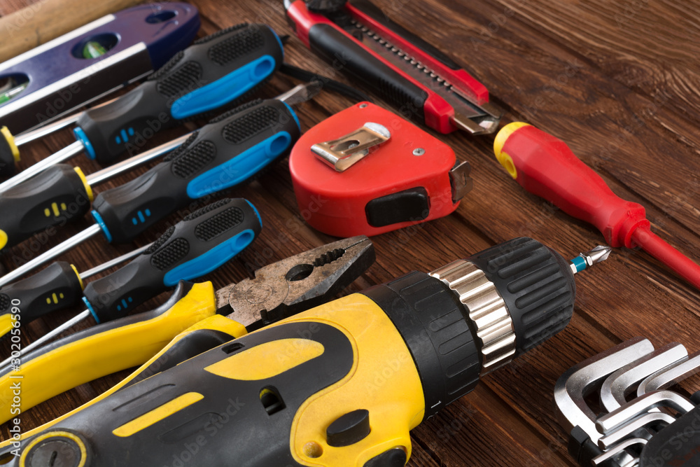Work tool of the wizard. Screwdrivers, pliers, wire cutters, building level, tape measure, hammer, wrenches, square and other tools on a wooden surface. Free space for text. Work tool of the wizard. Screwdrivers, pliers, wire cutters, building level, tape measure, hammer, wrenches, square and other tools on a wooden surface. Free space for text.
