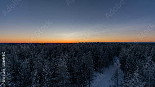 Forests and a snowy road in winter after sunset in Finland