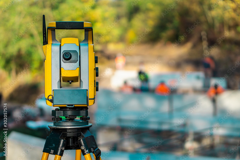 Fototapeta premium Surveyor engineer with equipment (theodolite or total positioning station) on the construction site of the road, building or bridge with construction machinery background