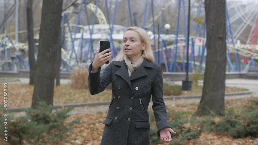 Woman blogger in a deserted autumn Park using a smartphone talking on video chat. Woman blogger in a deserted autumn Park using a smartphone talking on video chat.