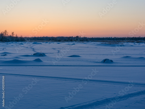 Snowy frozen sea with ski tracks in Finland at sunset time