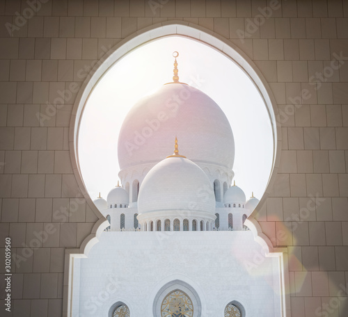 Beautiful view through a white marble arch at Sheikh Zayed Mosque in Abu Dhabi, United Arab Emirates. sunny day