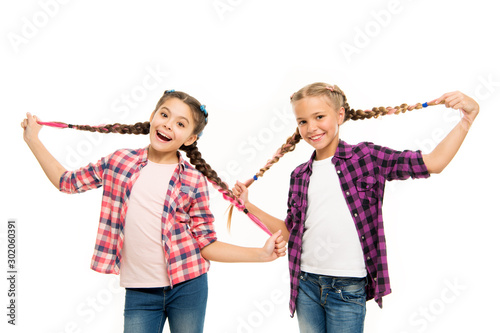 Such a long hair. Happy little girls wear plaited hair. Cute small childred hold hair braids. Luxurious hair extensions. Hairdressing salon for kids photo