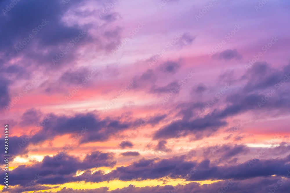Fototapeta premium Clouds of different tiers in warm tones of sunset with the sun.