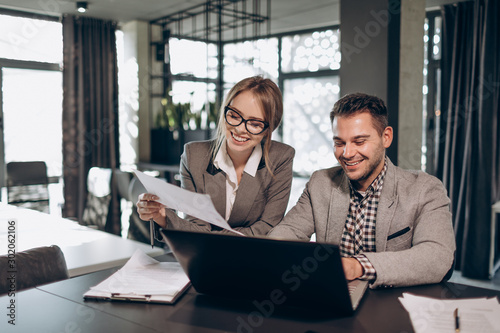 Male and female business partners working in office by a laptop