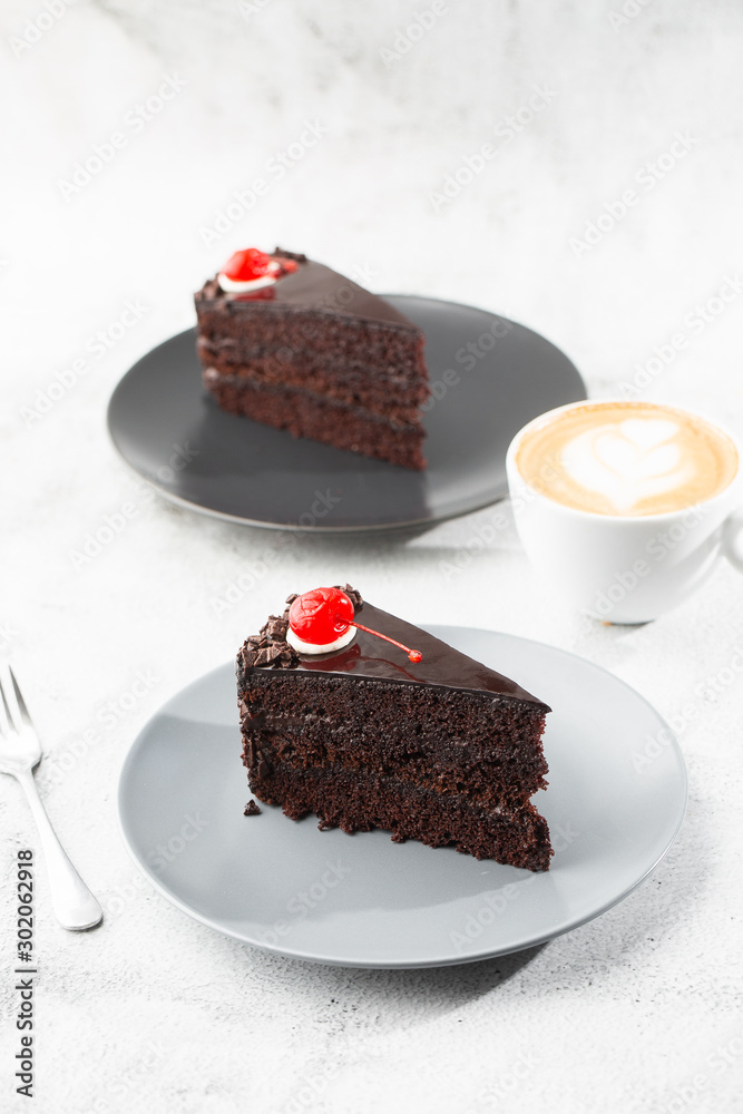 A slice of delicious chocolate cake with cherry on top on marble background. Piece of Cake on a Plate. Sweet food. Sweet dessert. Close up. Cafe menu. vertical photo.