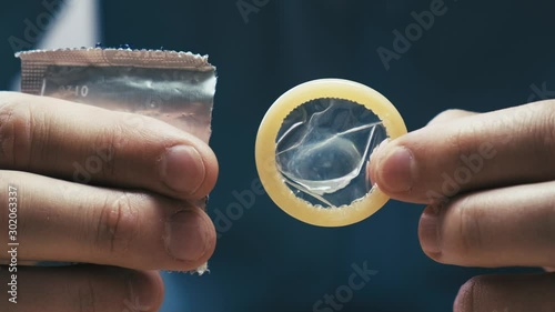 Male hands take out a condom from the packaging. Contraception and protected sex concept