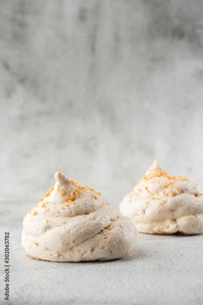 French meringue cookies, macro shot on bright marble background. Tray of meringues. Closeup meringue photo. Dessert background. Sweets. Food. Flat lay and copy space. Top view. Vertical