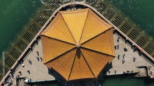 Rotating ascending drone shot of spectacular historic Zhanqiao pavilion, beautiful coastal scenery and landmark destination in Qingdao, culture and architecture in China photo