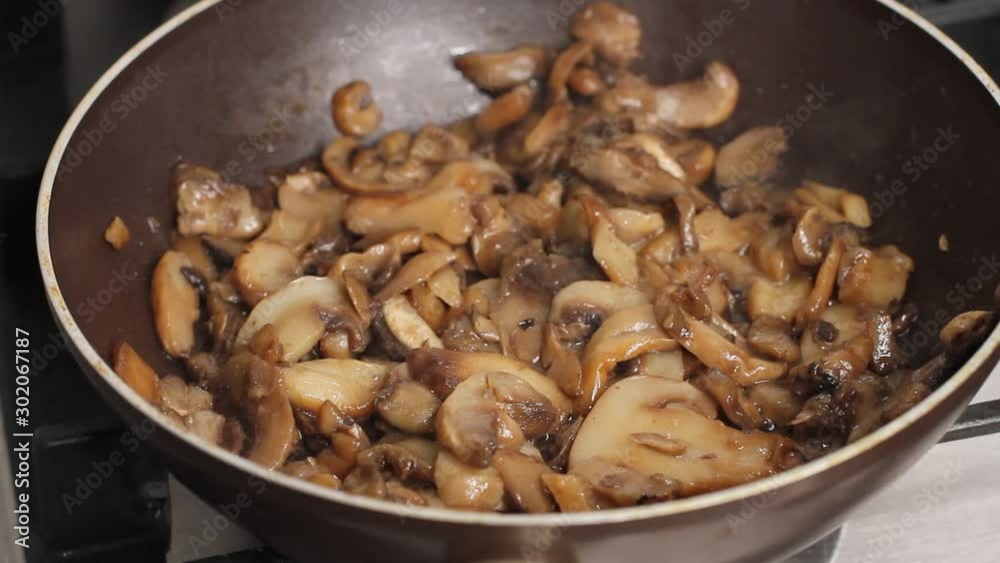 Mushrooms being cooked in frying pan in kitchen, delicious dish in olive oil and sauce Mushrooms being cooked in frying pan in kitchen, delicious dish in olive oil and sauce