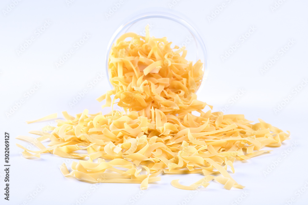 Fototapeta premium Glass jar filled with dry rotini yellow pasta over isolated white background