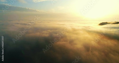 Drone flying over the clouds at sunset. The sun is hidden behind the clouds at sunset fog.