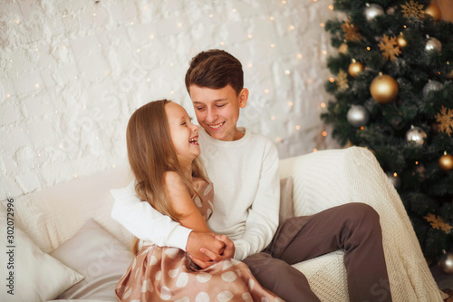 Happy laughing and hugging brother and sister in a christmas interior with lights. The concept of Christmas and New Year.
