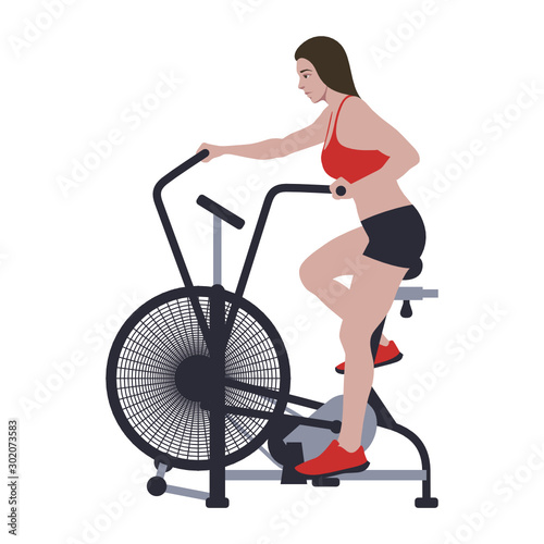 Woman on air bike training CrossFit workout. Healthy life motivation. Assault bike riding sports activity.