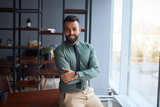 portrait of confident young handsome middle eastern businessman standing in office, looking at camera, successful team leader wearing formal wear, posing for photo at workplace
