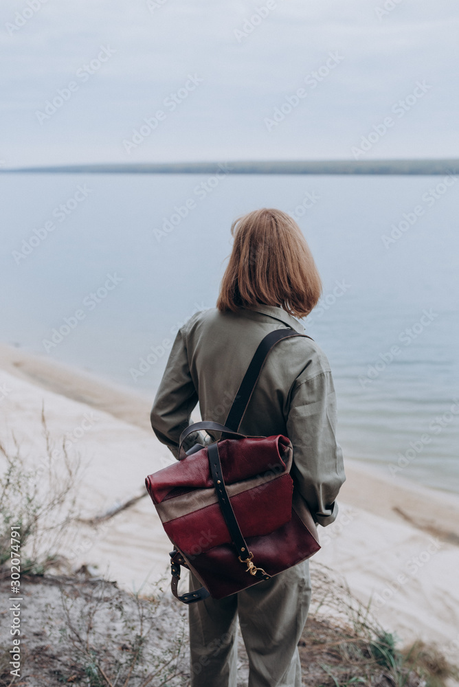 Fototapeta premium a woman with a leather bag walks on the shore of the lake