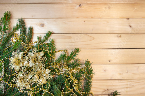 Christmas decoration - twigs of spruce, golden flowers and golden chain on a wooden background