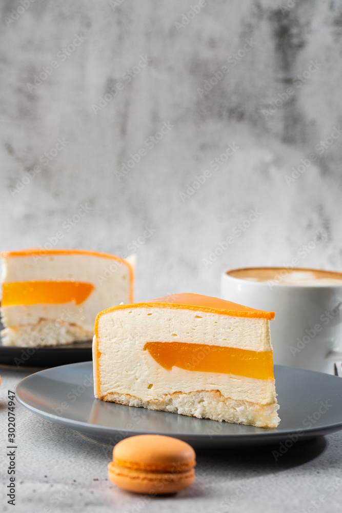 Elegant Cake with coconut, passion fruit, mangoes and bananas, covered with chocolate glaze. Slice of orange layered cake on marble background. Wallpaper for pastry cafe or cafe menu. vertical.
