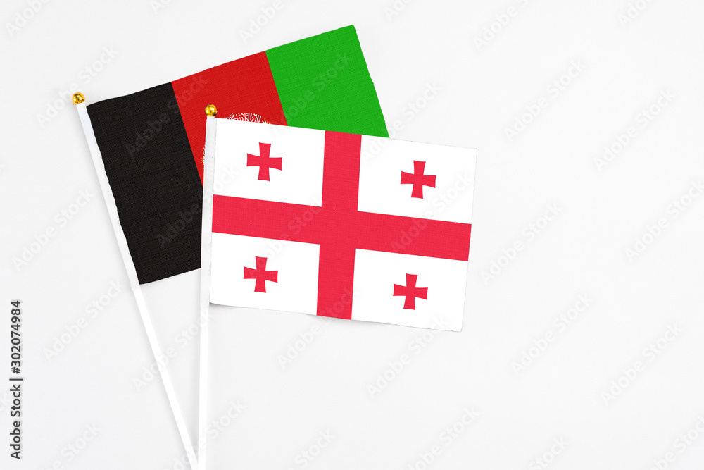 Georgia and Afghanistan stick flags on white background. High quality fabric, miniature national flag. Peaceful global concept.White floor for copy space.