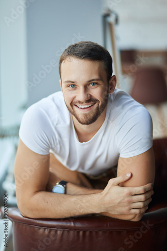Portrait of a confident and successful young businessman and entrepreneur at a specious modern office, dressed in a casual outfit. Smiling cheerfully and looking straight ahead.