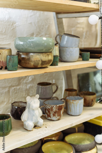 Ceramic bear and handmade dishes on the shelf of the pottery workshop.